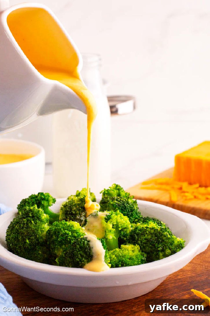This creamy cheese sauce is a true kitchen staple. Pour it over broccoli, stir it on pasta for quick mac n' cheese, or serve it as a dip for pretzels and chips! #cheesysauce #cheesesauce pouring cheese sauce over broccoli