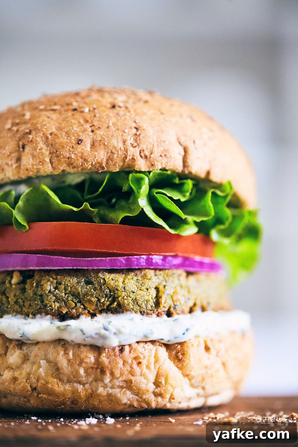 Crispy Falafel Tahini Burgers with Refreshing Tzatziki 2 Falafel burger with tzatziki on a wooden serving board