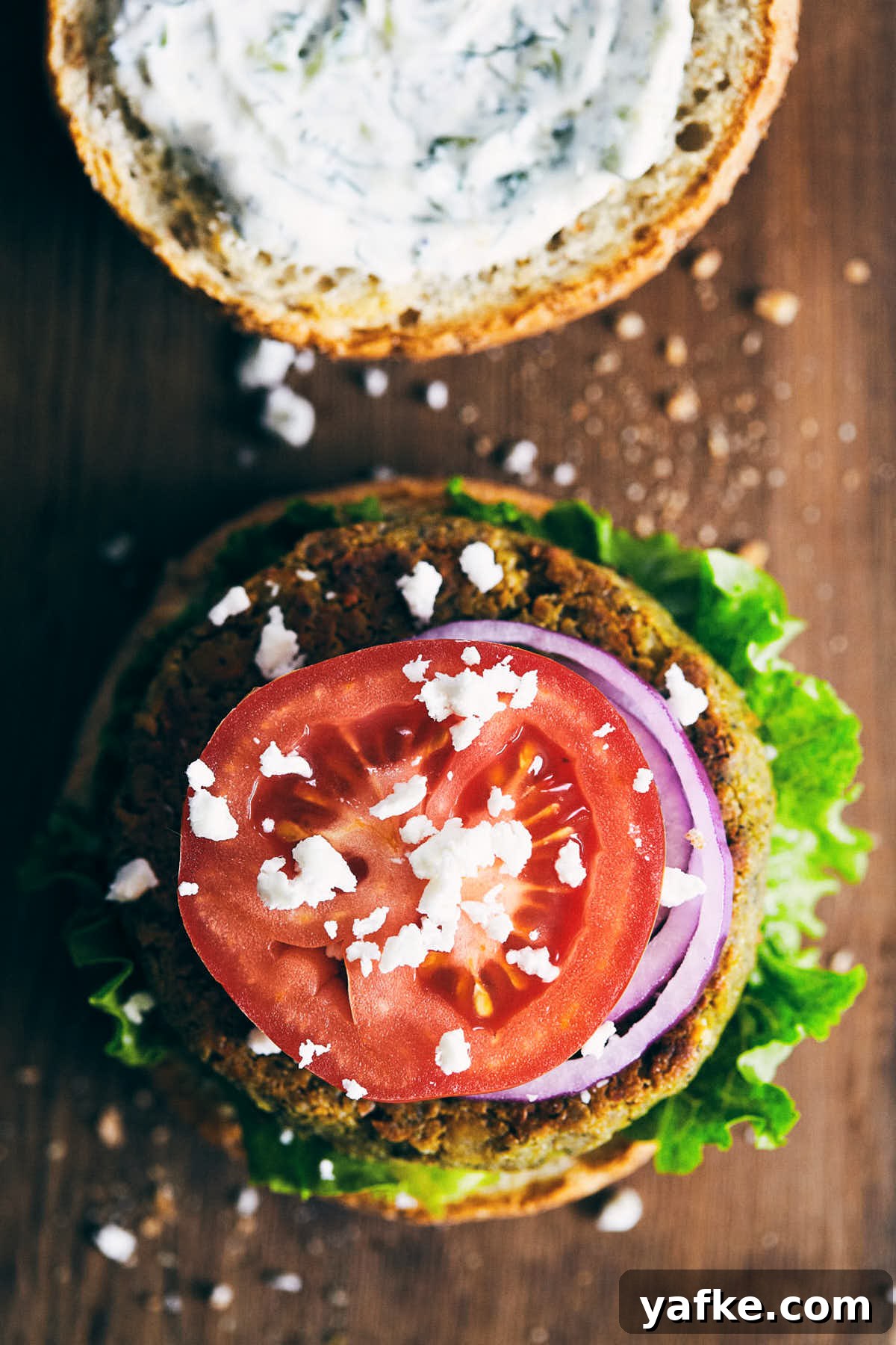 Crispy Falafel Tahini Burgers with Refreshing Tzatziki 3 Top down view of burger being dressed with feta