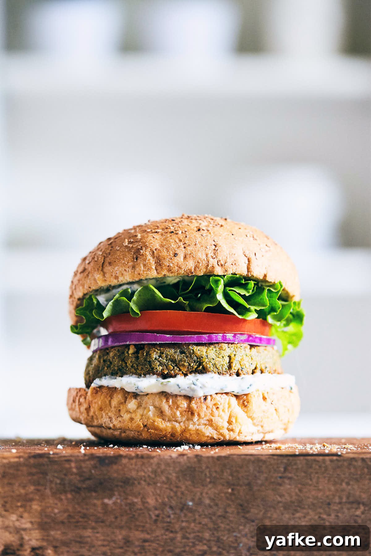 Crispy Falafel Tahini Burgers with Refreshing Tzatziki 5 Falafel burger with tzatziki on a wooden serving board