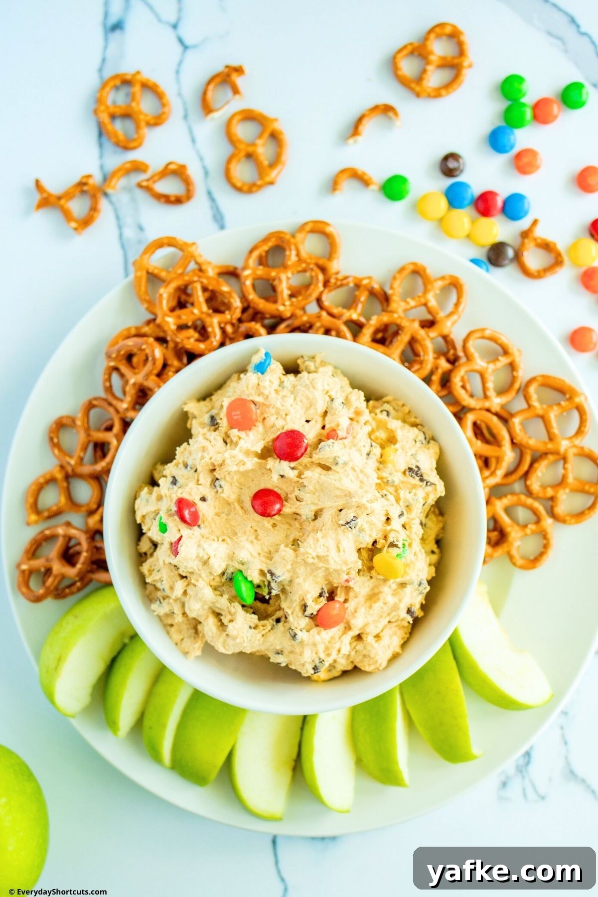 No-Bake Monster Cookie Dough Dip Recipe for Parties 10 apple slices and pretzels on a plate with cookie dough