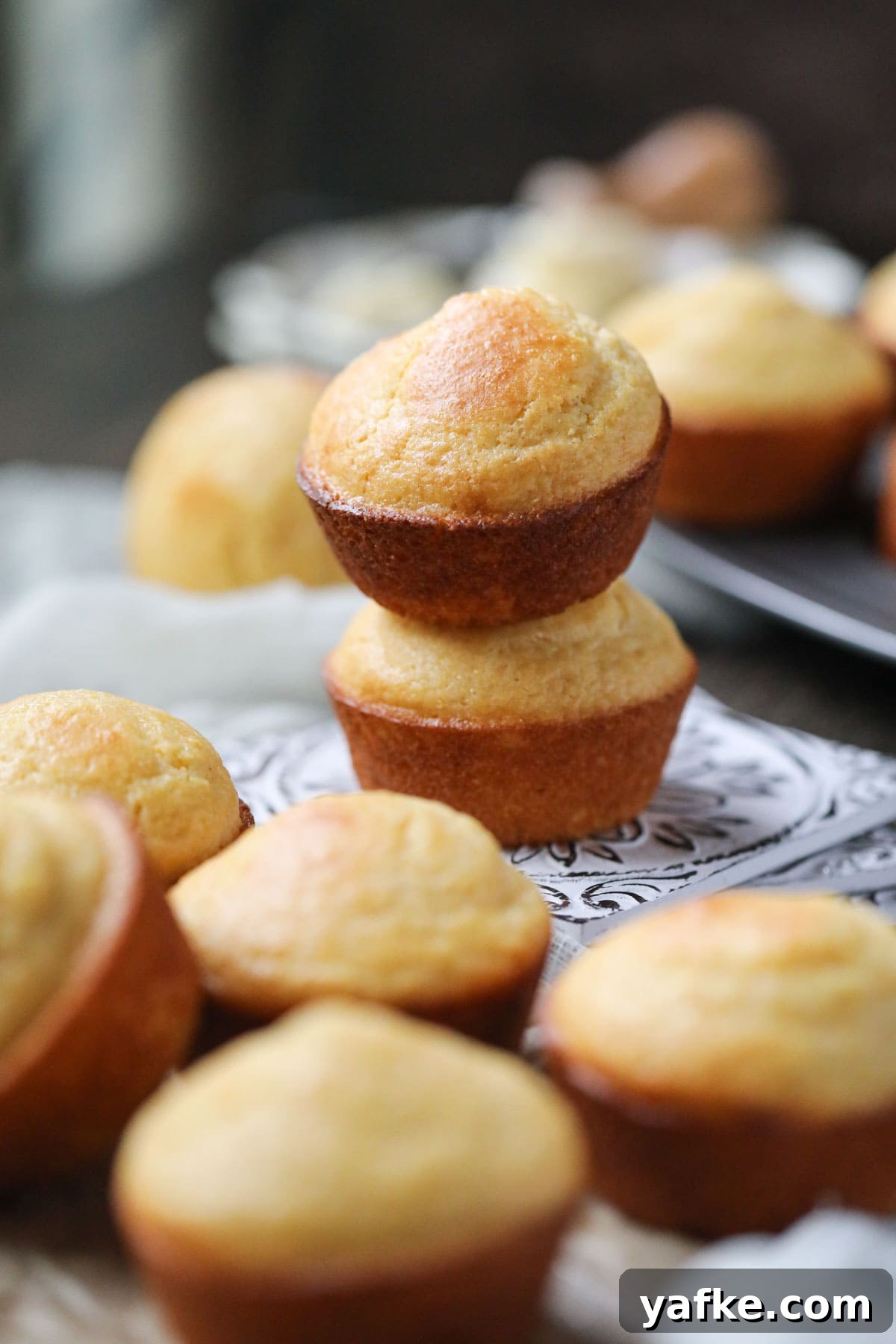 Moist Southern Sweet Cornbread Muffins Recipe 2 buttermilk cornbread muffins arranged on a wooden surface.