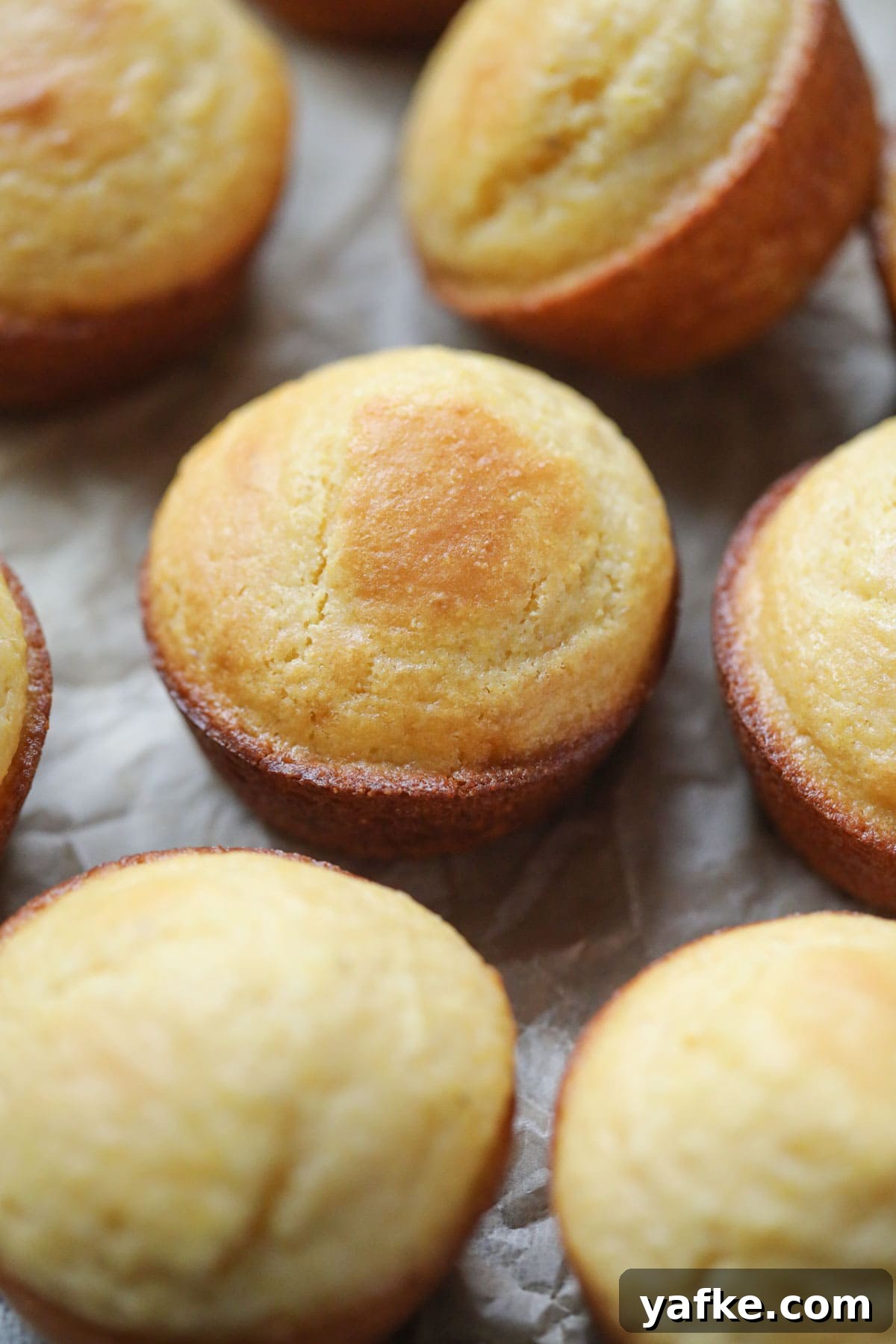 Moist Southern Sweet Cornbread Muffins Recipe 7 buttermilk cornbread muffins arranged on a wooden surface.