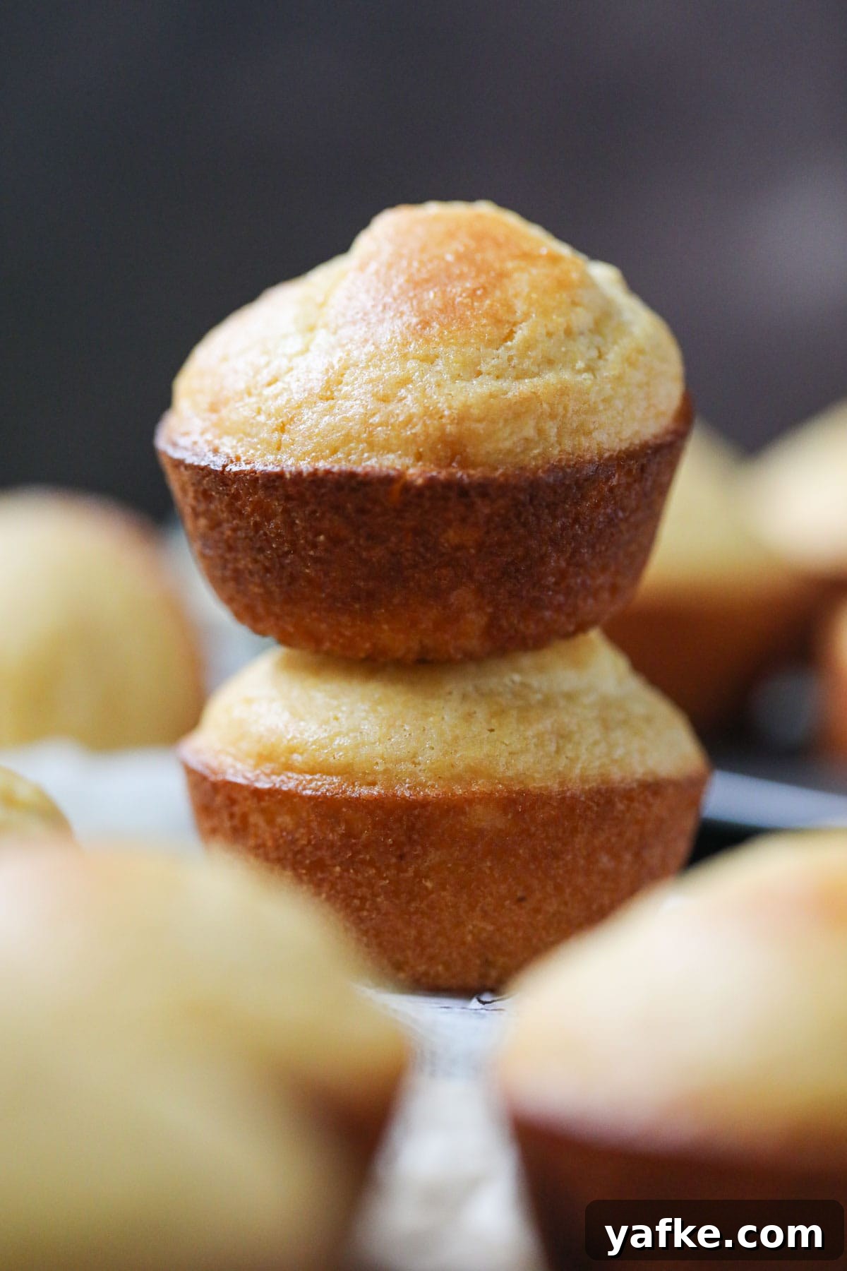 Moist Southern Sweet Cornbread Muffins Recipe 8 buttermilk cornbread muffins stacked on parchment paper.