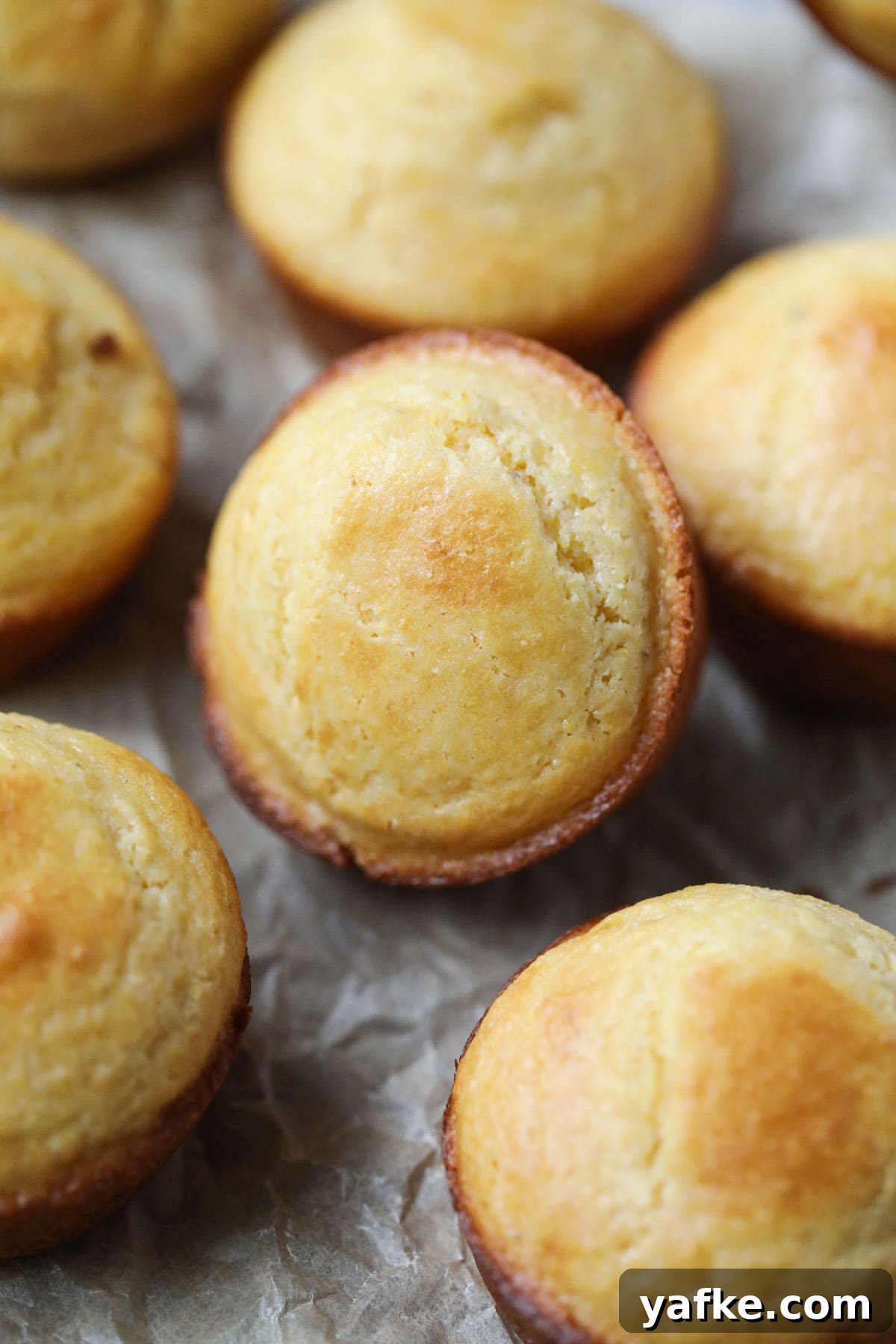 Moist Southern Sweet Cornbread Muffins Recipe 9 buttermilk cornbread muffins arranged on a wooden surface.