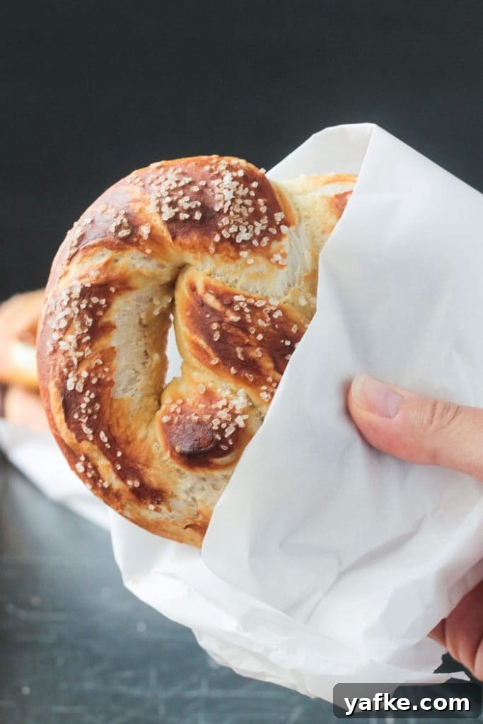 2017's Most Popular Plant-Based Recipes 10 Hand holding a soft baked pretzel partially wrapped in a piece of parchment paper.