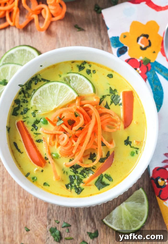 2017's Most Popular Plant-Based Recipes 11 Bowl of Coconut Curry Soup with golden yellow broth, bell red peppers, spiralized sweet potato noodles, and garnished with lots of chopped cilantro and two lime wedges.
