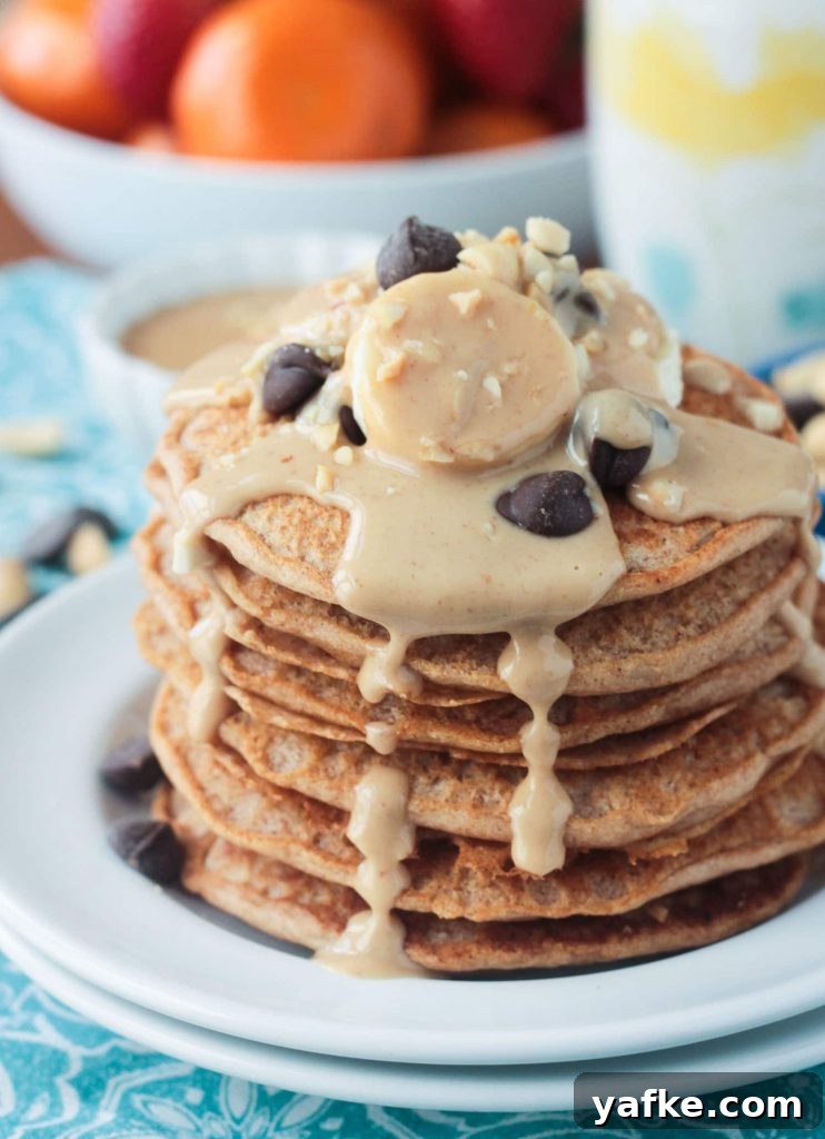 2017's Most Popular Plant-Based Recipes 4 Stack of peanut butter pancakes topped with bananas, chocolate chips, and homemade maple peanut butter syrup dripping down the sides.