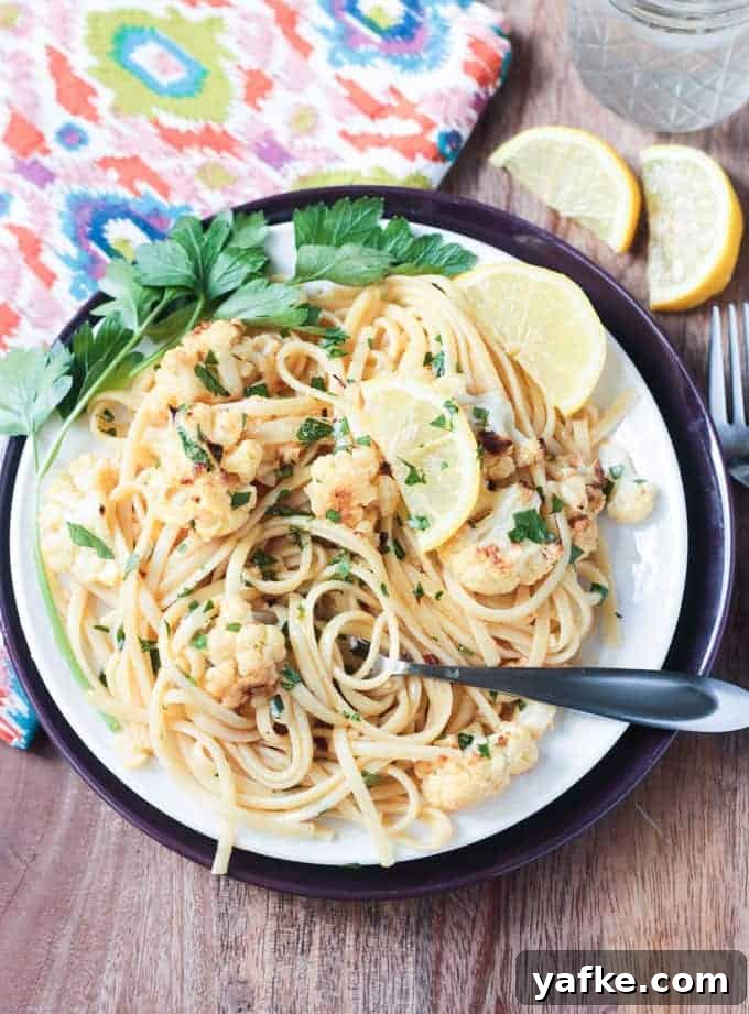 2017's Most Popular Plant-Based Recipes 7 Plate of Cauliflower Scampi in Lemon Garlic White Wine Sauce garnished with wedges of lemon and fresh parsley.