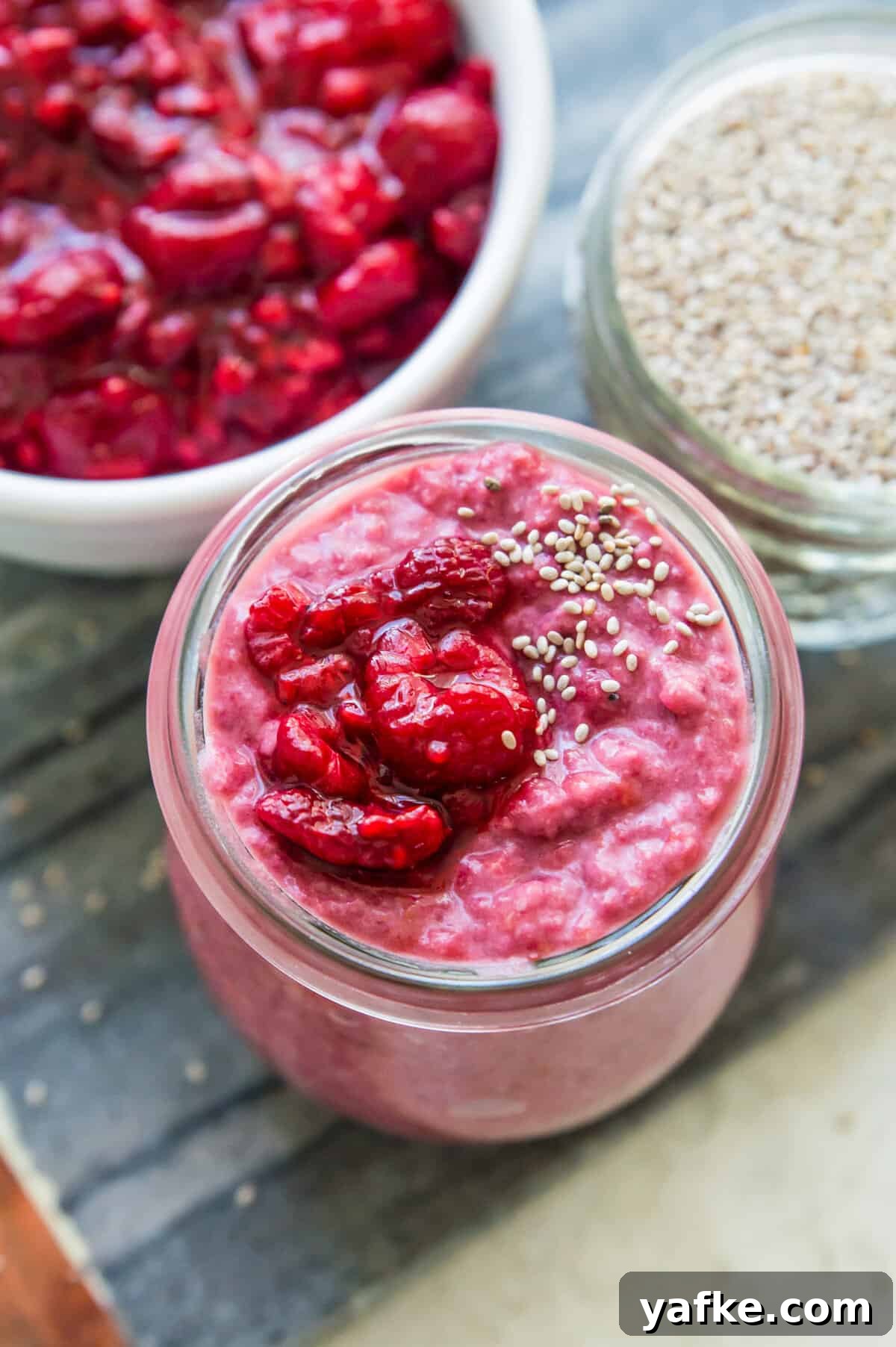 5-Ingredient Raspberry Chia Pudding Recipe 9 A jar of pink chia pudding topped with fresh raspberries and white chia seeds.