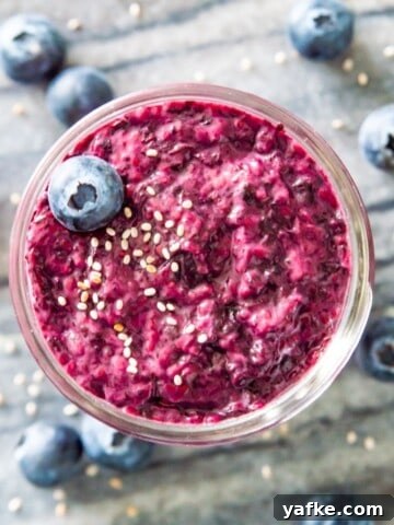 A jar of blueberry chia jam topped with a fresh blueberry and white chia seeds.