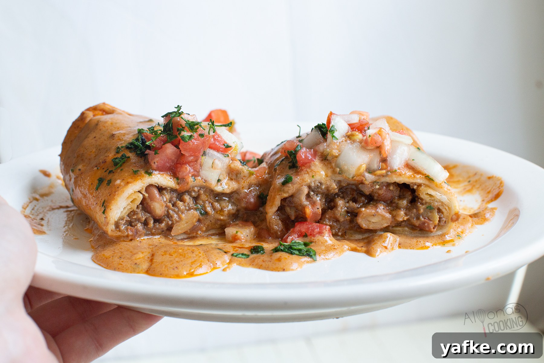 Beef Enchiladas with seasoned ground beef and smashed pinto beans rolled up in flour tortillas then smothered in a red chili sauce. This is the easy Tex-Mex way to make a beef enchilada recipe baked in a casserole. It's one of our Best-Loved recipes perfect for weeknight dinner or a special crowd! filling of a ground beef enchilada