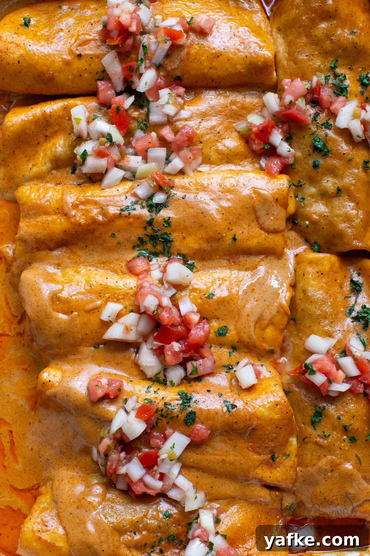 Beef Enchiladas with seasoned ground beef and smashed pinto beans rolled up in flour tortillas then smothered in a red chili sauce. This is the easy Tex-Mex way to make a beef enchilada recipe baked in a casserole. It's one of our Best-Loved recipes perfect for weeknight dinner or a special crowd! beef enchiladas with pico de gallo