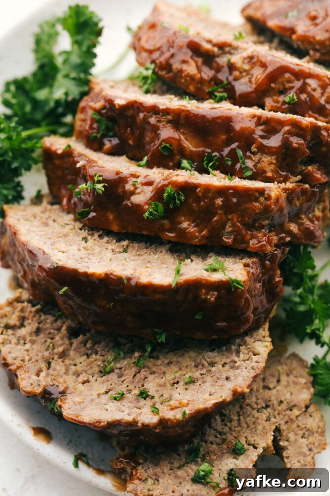 The whole meatloaf sliced up on a plate with parsley garnish.