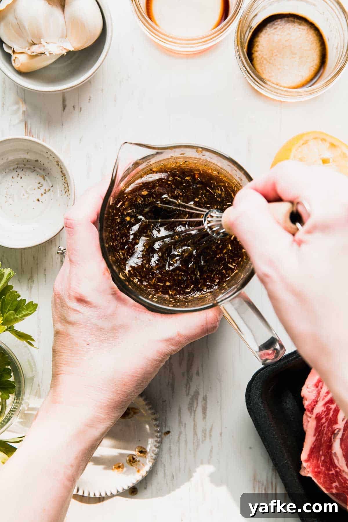Gluten-Free Steak Marinade Recipe for Juicy Grilled Steak 2 Hand whisking gluten free steak marinade in a glass measuring cup, surrounded by empty prep dishes.