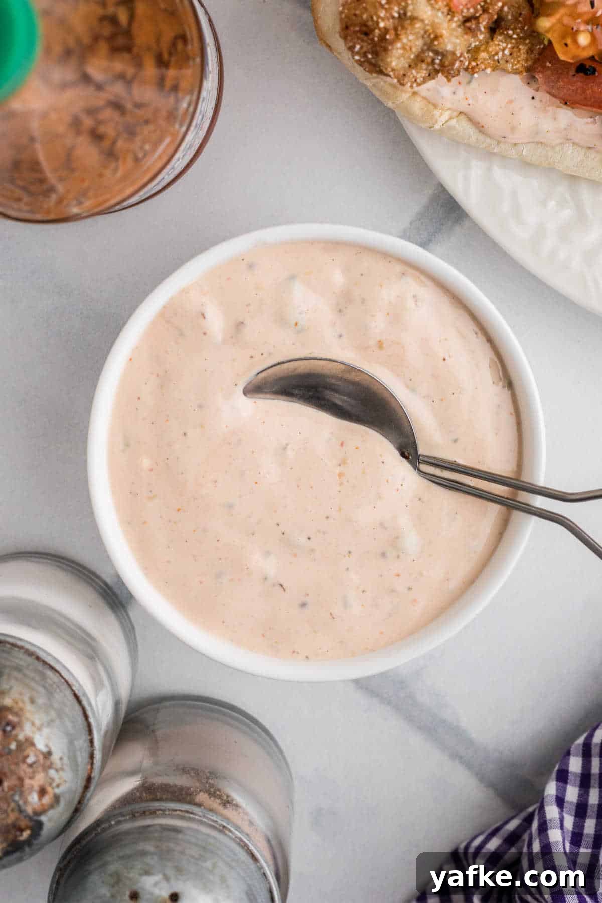 Creamy Remoulade Sauce Recipe for Seafood and Sandwiches 10 A small bowl of remoulade sauce with a spoon resting in it.