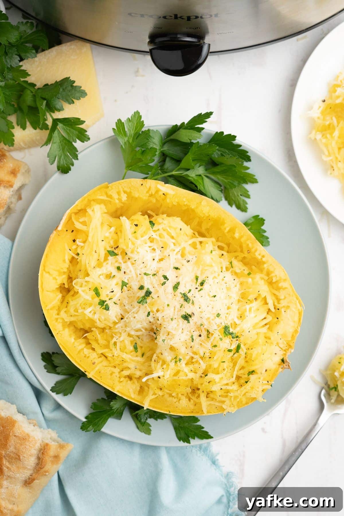 Slow Cooker Spaghetti Squash Recipe 2 Slow cooker spaghetti squash served up on a blue plate with some parsley for garnish.