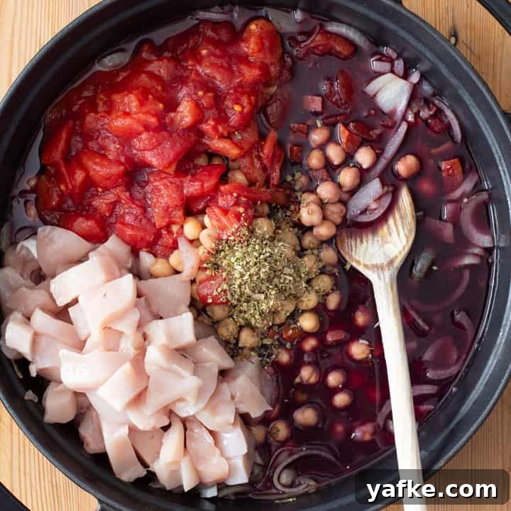 Spanish-Style Chicken, Chorizo, and Chickpea Stew 3 raw ingredients inside a black pan for making chicken and chorizo stew