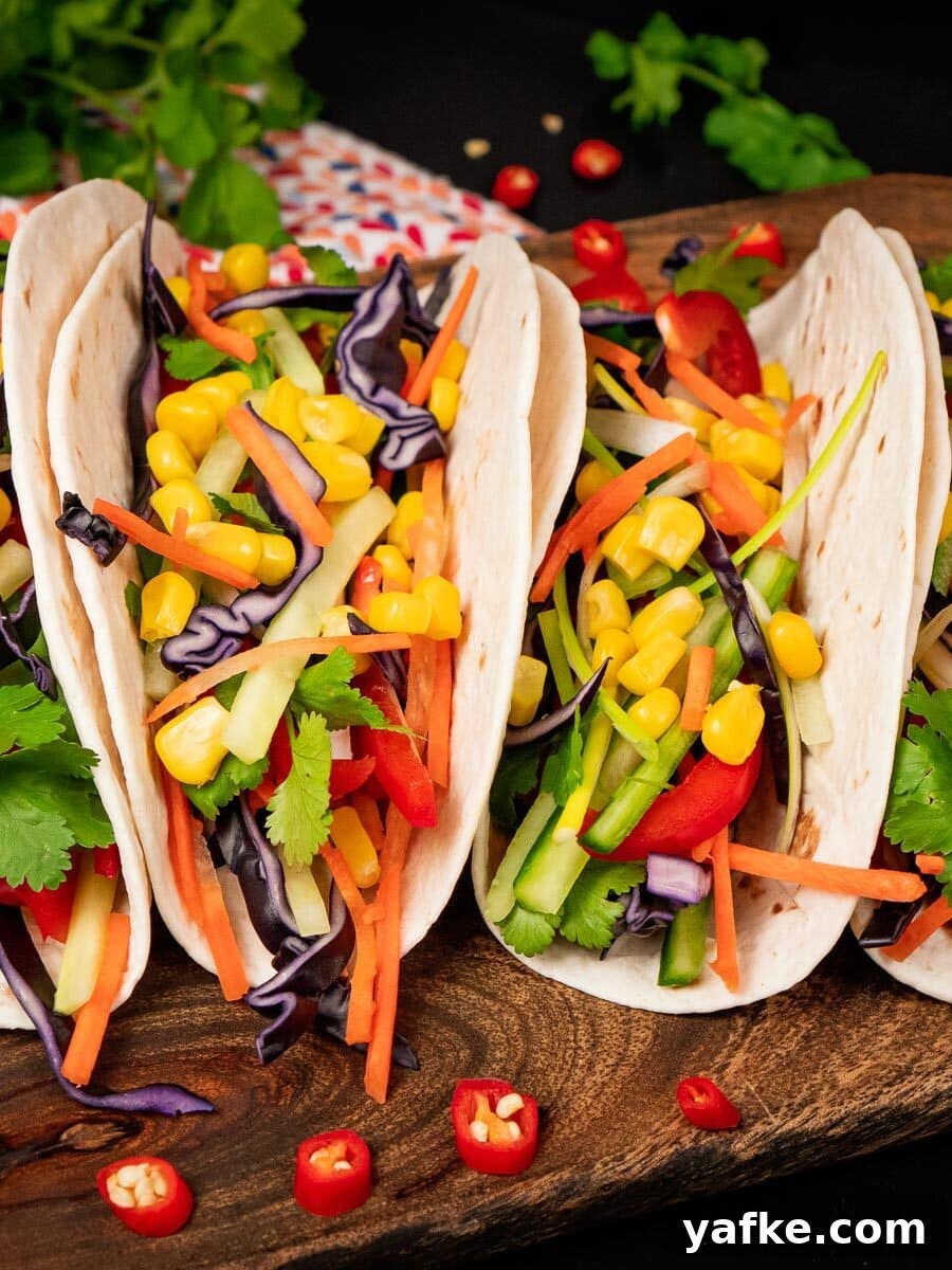 Crispy Shrimp Tacos with Sweet Chili Sauce 14 Four taco wraps filled with red,slices of cucumber, spring onion, coriander, red cabbage, grated carrot and sweet corn served on a wooden chopping board
