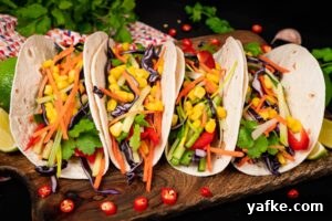 Crispy Shrimp Tacos with Sweet Chili Sauce 8 Four taco wraps filled with red,slices of cucumber, spring onion, coriander, red cabbage, grated carrot and sweet corn served on a wooden chopping board