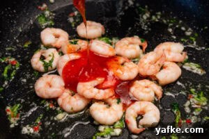 Crispy Shrimp Tacos with Sweet Chili Sauce 7 Sweet chilli sauce being poured over the top of king prawns frying in a pan