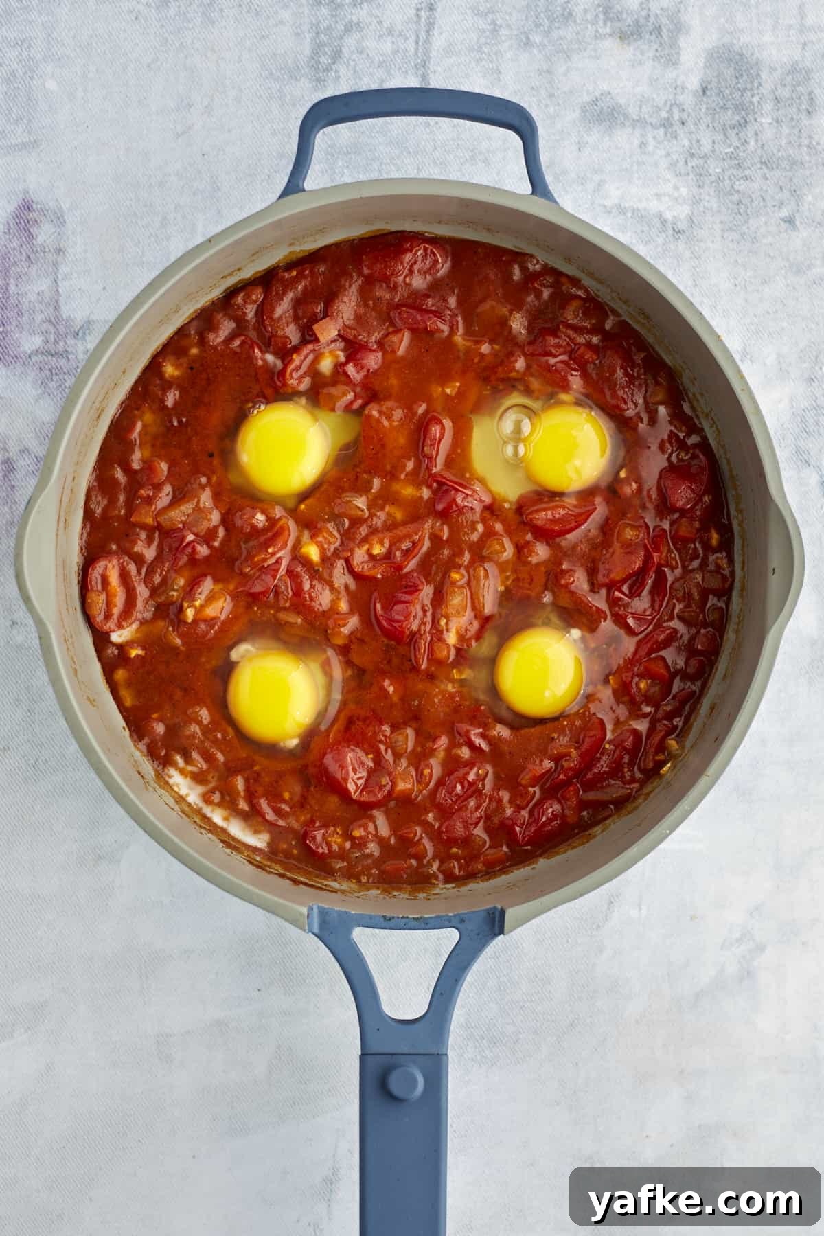 One-Pan Shakshuka with Feta and Fresh Herbs 7 four eggs cracked into shakshuka sauce in a large pot