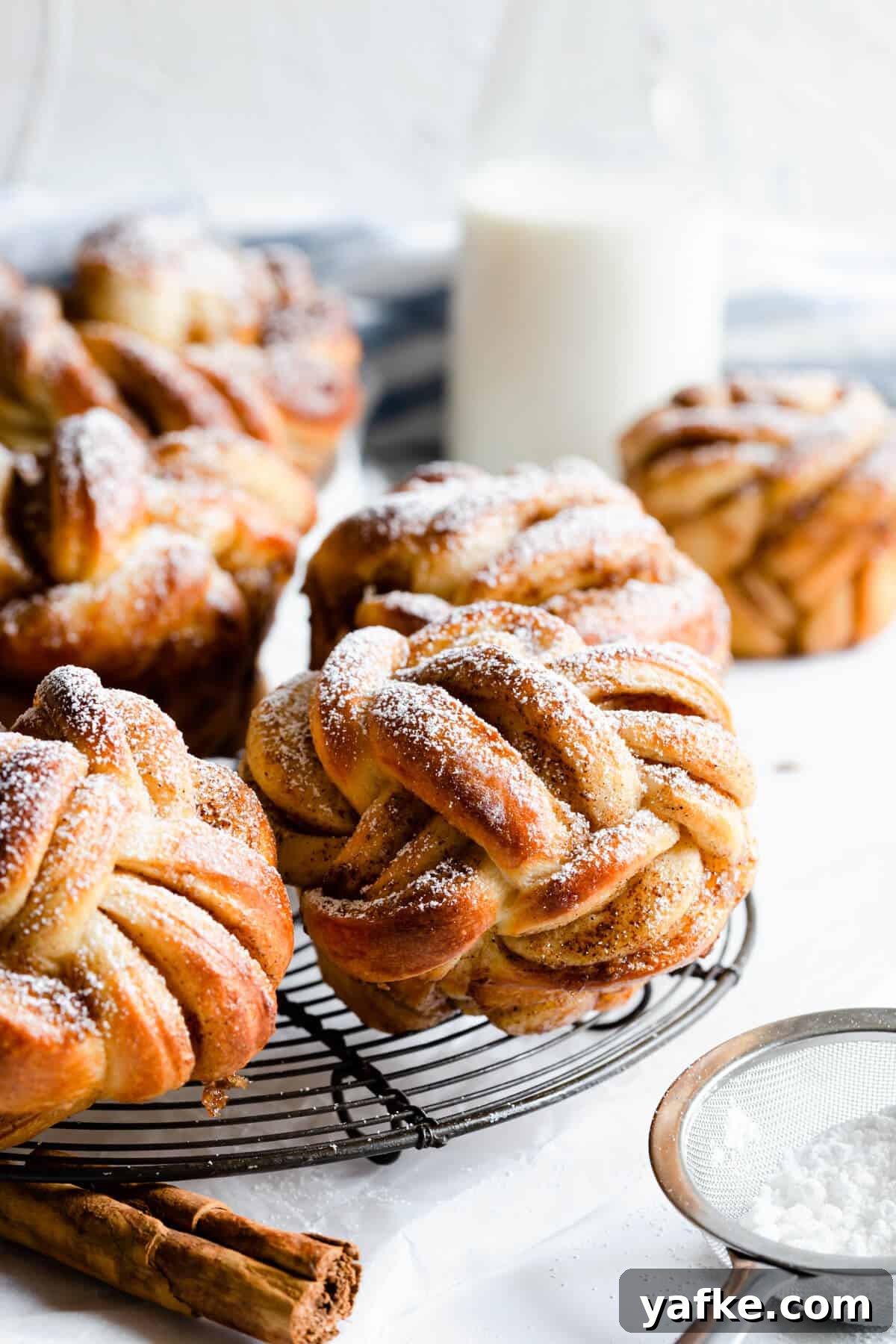 side shot of cinnamon buns shaped into knots and dusted with icing sugar