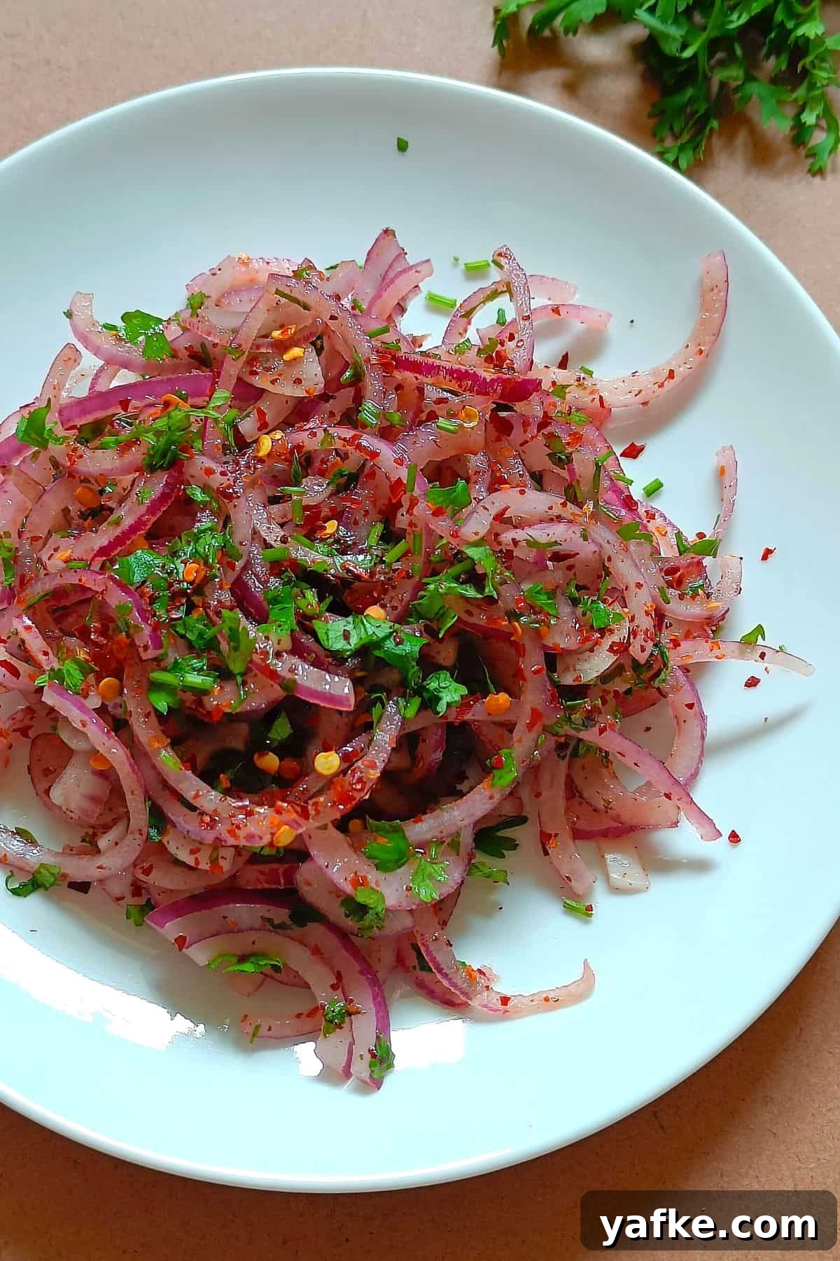 Turkish Sumac Marinated Red Onions Recipe 2 Image showing onion salad with sumac served on a white plate.