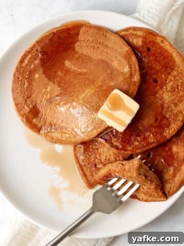 Single serve pumpkin pancakes on a plate with maple syrup.
