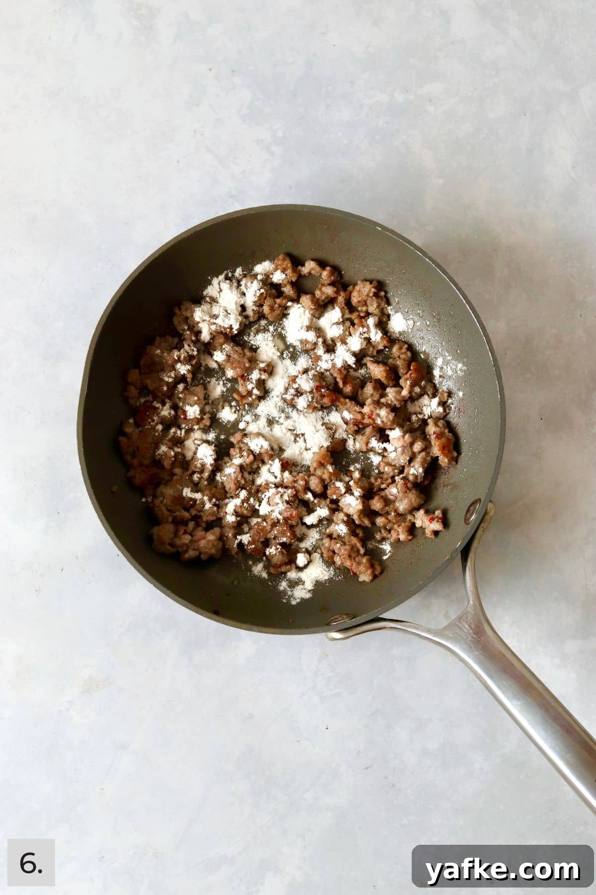 Single-Serve Biscuits and Sausage Gravy for One 9 Flour sprinkled over cooked sausage in a skillet.