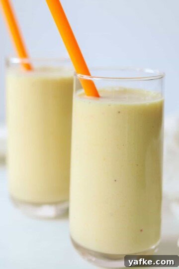 two glasses of banana peach smoothies with orange straws