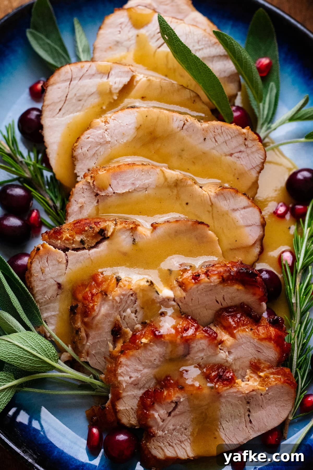 Juicy Maple Herb Air Fryer Turkey Breast 9 A close up of turkey breast slices with gravy over top with herbs arranged around the turkey.