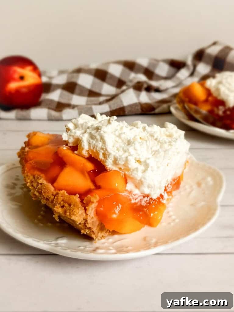 How to Make Authentic Amish Fresh Peach Pie 9 a full-sized photo of a slice of peach pie on a plate, another plate with pie in the background along with a towel and a peach.