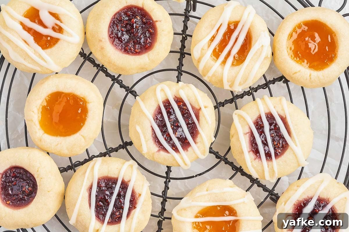 Which Sugar to Use for Cooking and Baking 3 A cooling rack holds an assortment of round thumbprint cookies with various fillings, including red and orange jams and white icing drizzles.