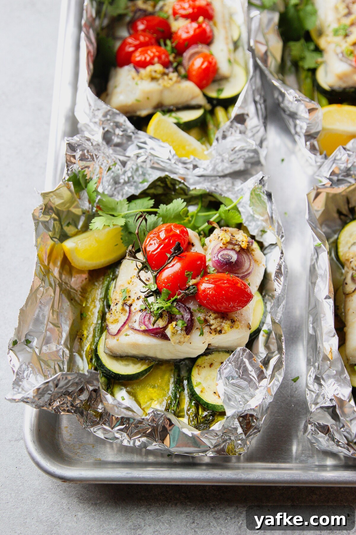 Foil-Baked Fish with Lemon, Garlic and Seasonal Vegetables 2 baked fish in foil with vegetables