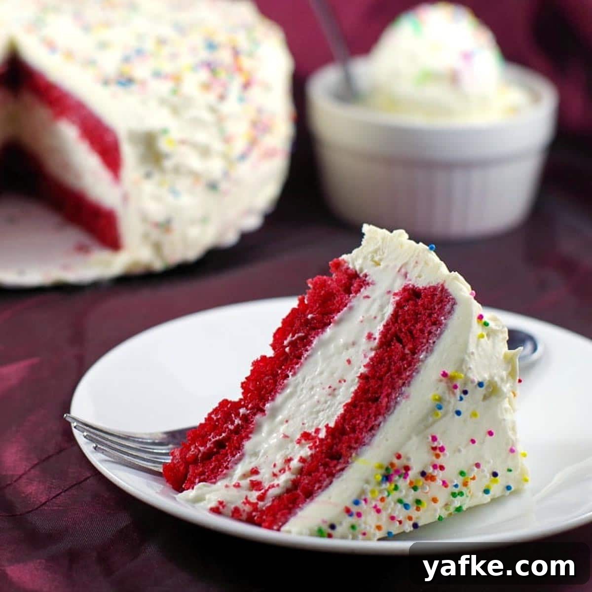 21 Patriotic Canada Day Desserts 6 Slice of red velvet ice cream cake with whole cake in the background and a bowl of no churn ice cream
