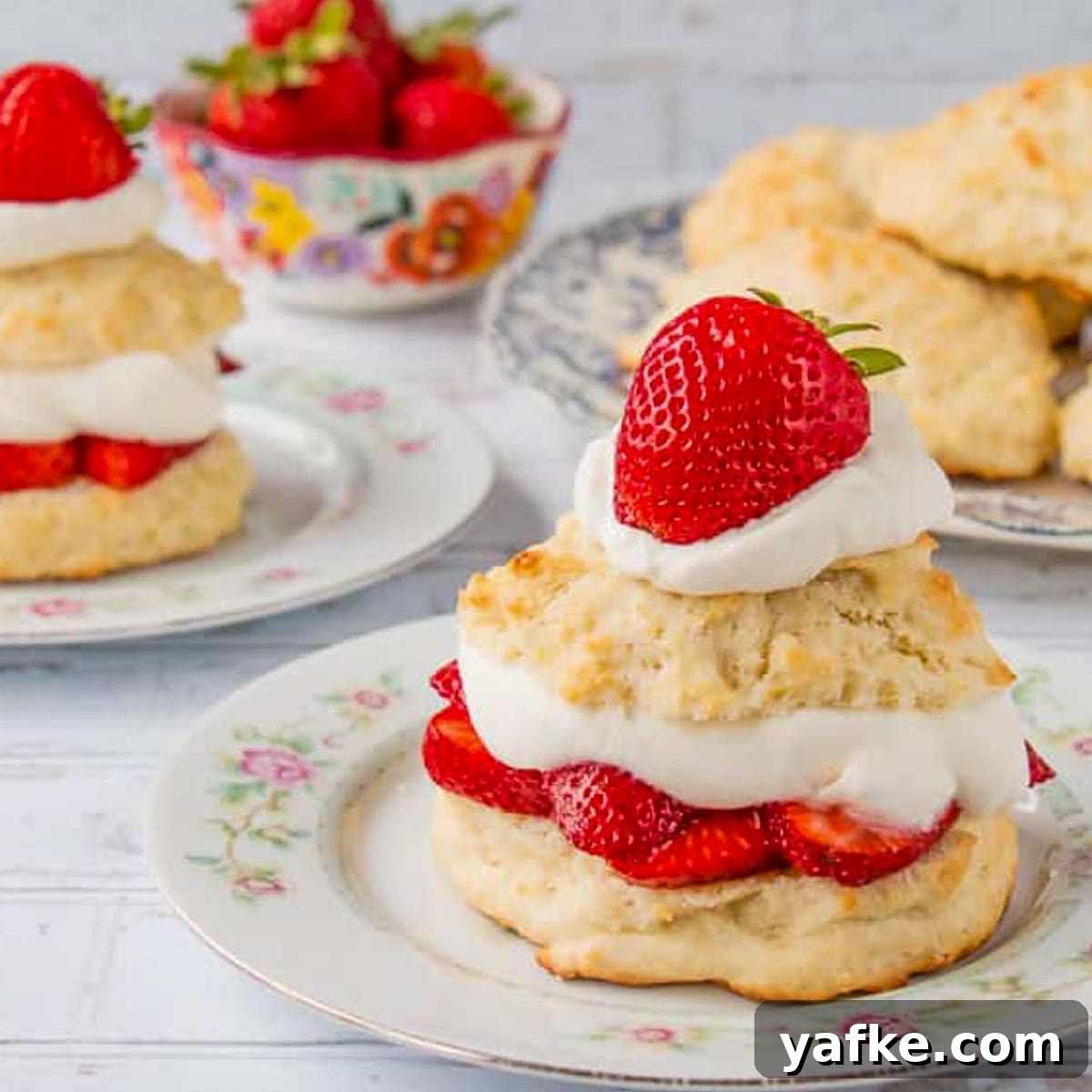 21 Patriotic Canada Day Desserts 7 2 strawberry shortcakes on white plates, with a bowl of strawberries in background