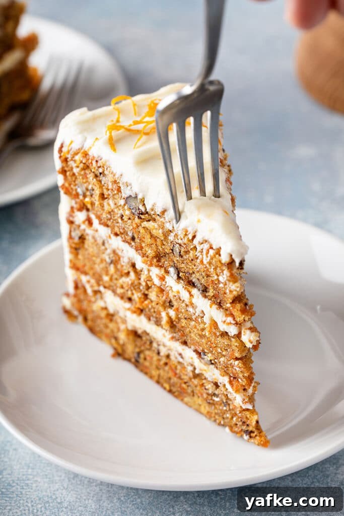 Carrot Cake Recipe with Grand Marnier Cream Cheese Frosting 4 Fork piercing a slice of three-layer carrot cake