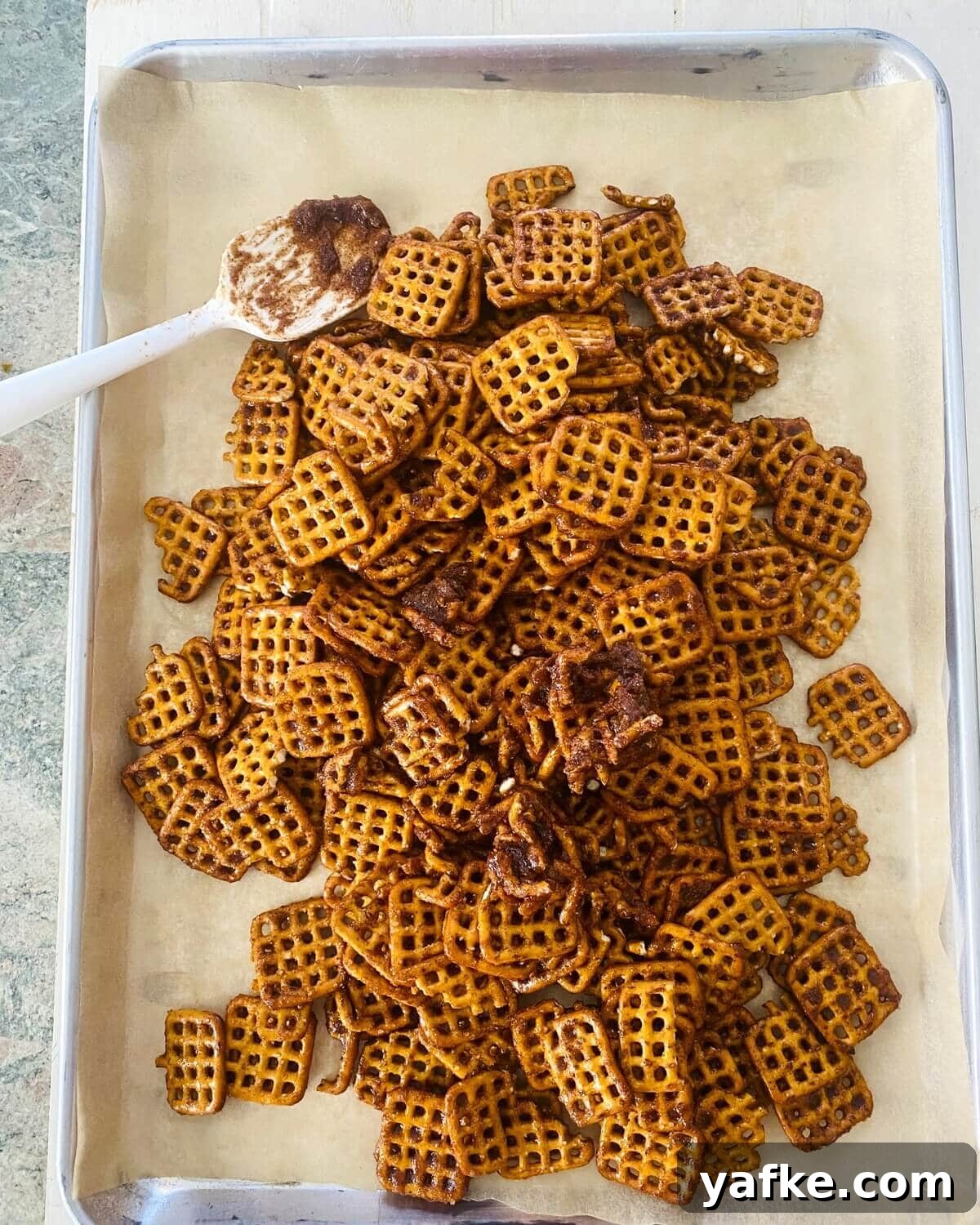 Pumpkin Spice Pretzels Drizzled with White Chocolate 7 pretzels on a baking sheet with pumpkin spice.