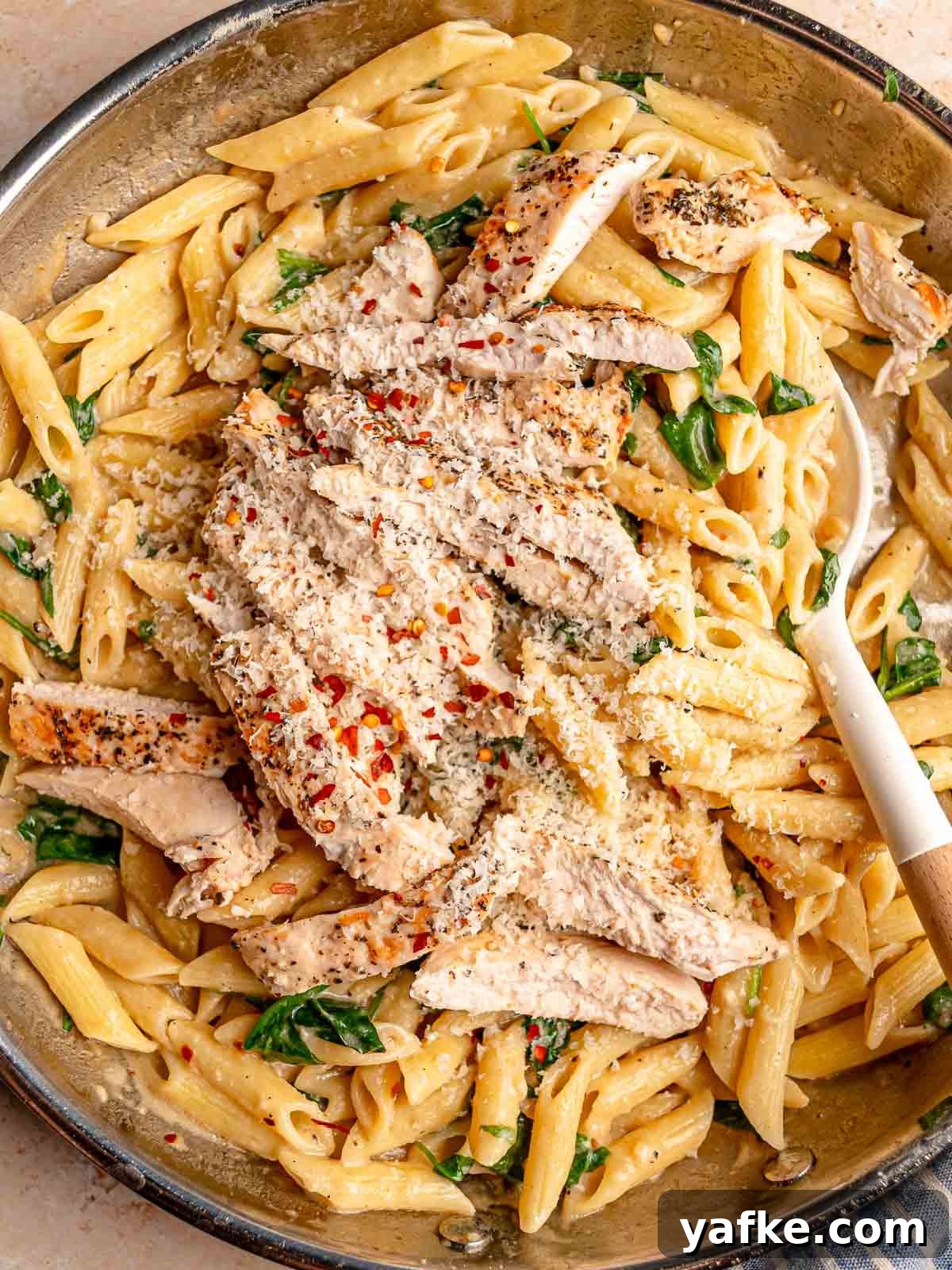 30-Minute Garlic Parmesan Chicken Pasta Recipe 2 Creamy garlic Parmesan chicken pasta with penne, spinach and sliced seasoned chicken topped with red pepper flakes and grated cheese.