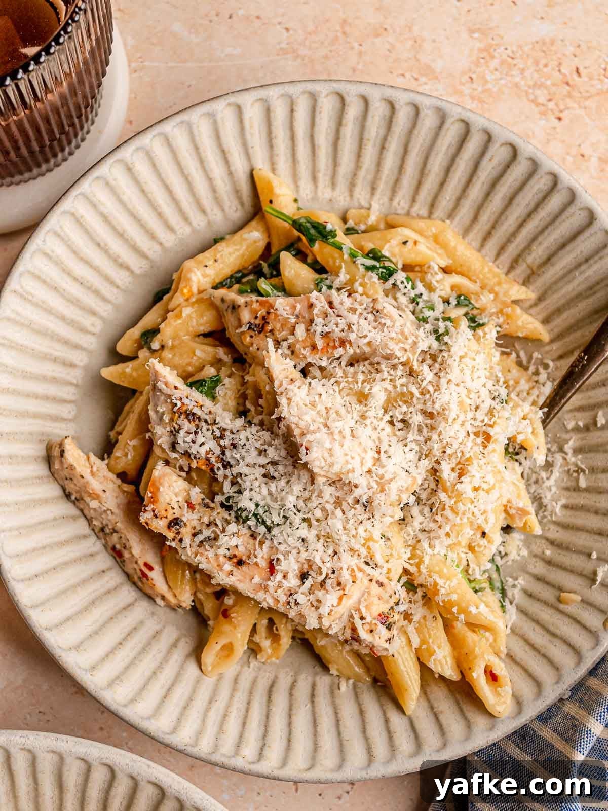 30-Minute Garlic Parmesan Chicken Pasta Recipe 8 Plate of creamy garlic Parmesan chicken pasta with penne and spinach, generously topped with freshly grated Parmesan.