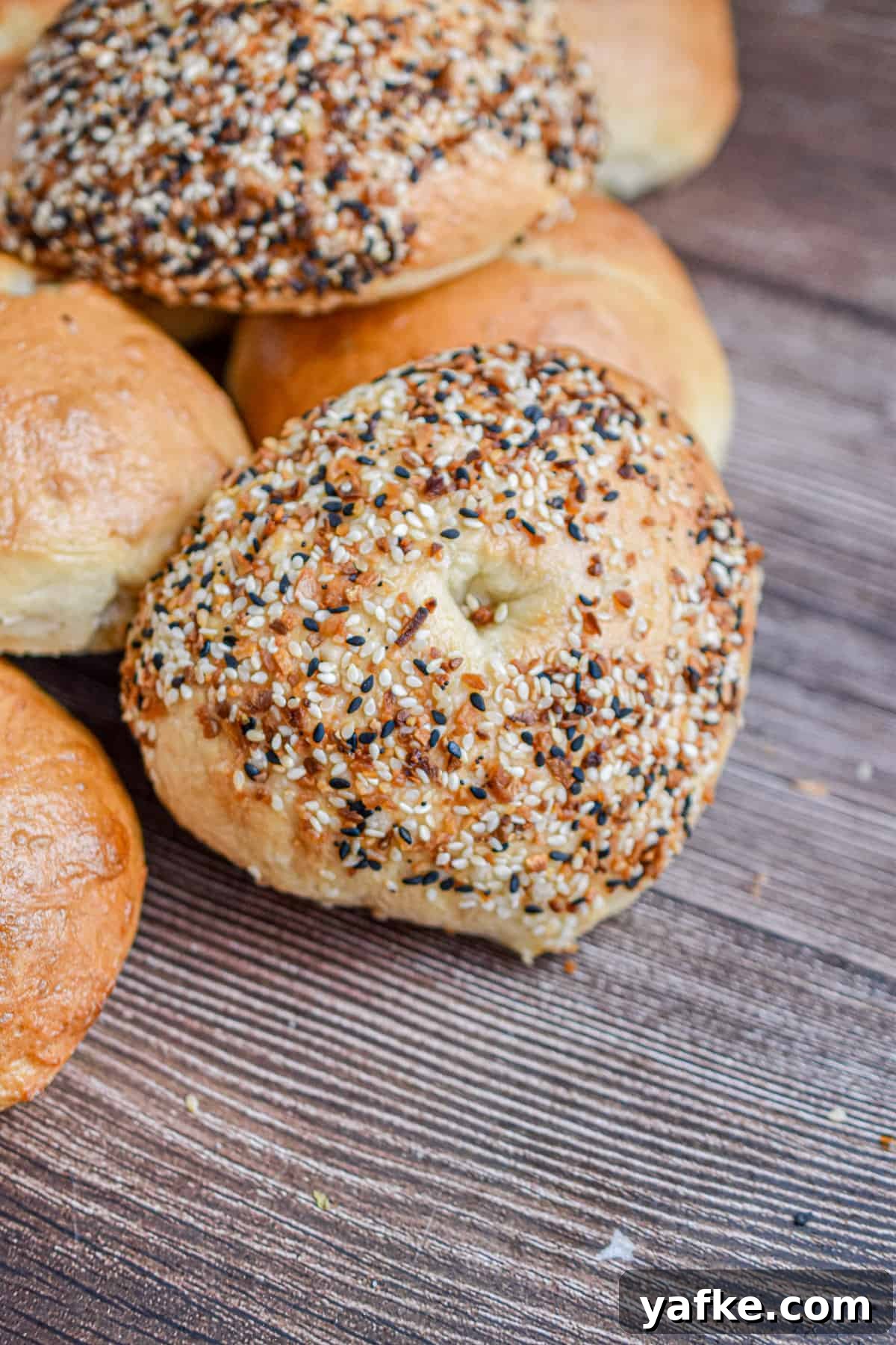New York-Style Bagels Made with Sourdough Discard 11 A sourdough discard bagel is covered with everything bagel seasoning and it is leaning against a pile of bagels.
