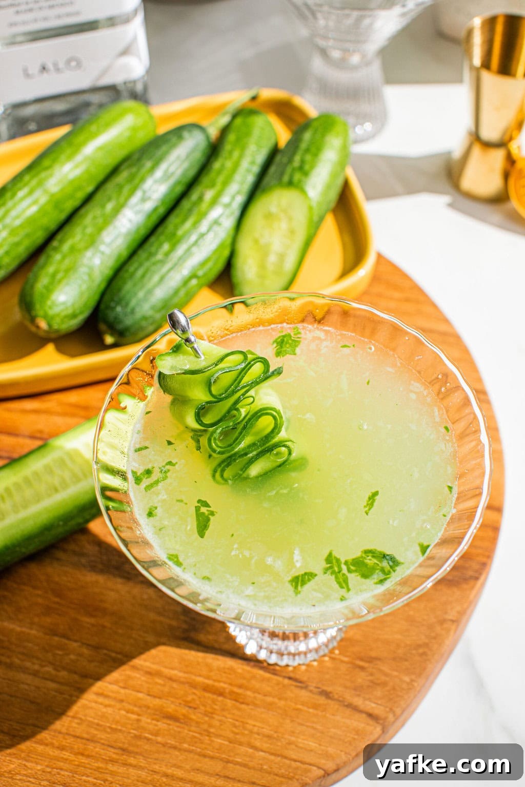 an overhead shot of cucumber spa martini with cucumbers in the background