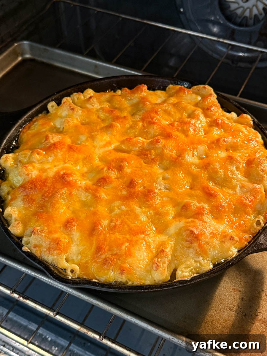 Southern Soul Food Baked Mac and Cheese Recipe 10 Southern soul food baked mac and cheese bubbling in the oven inside a cast iron skillet, with cheese browned and slightly crisp on top.