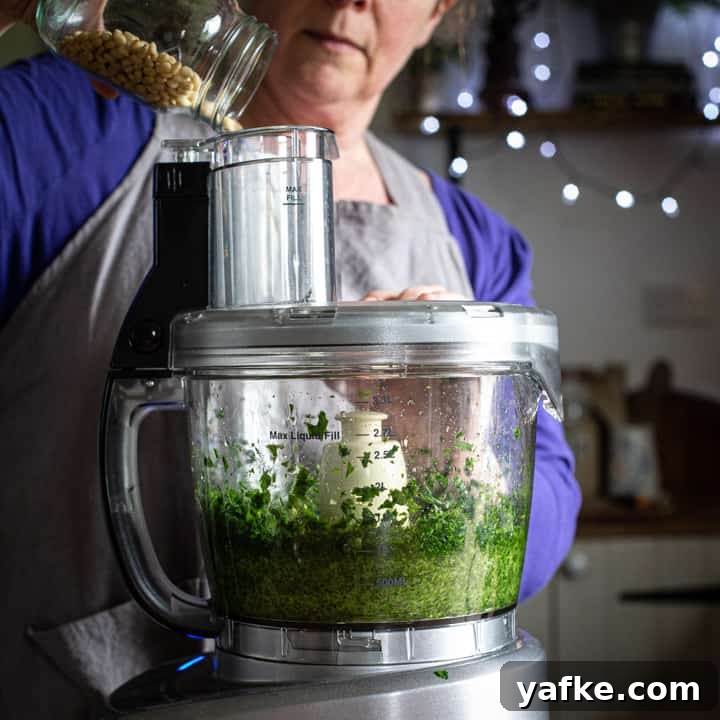 Wild Garlic Pesto Recipe for Spring 7 woman in grey pouring nuts into a food processor to make pesto