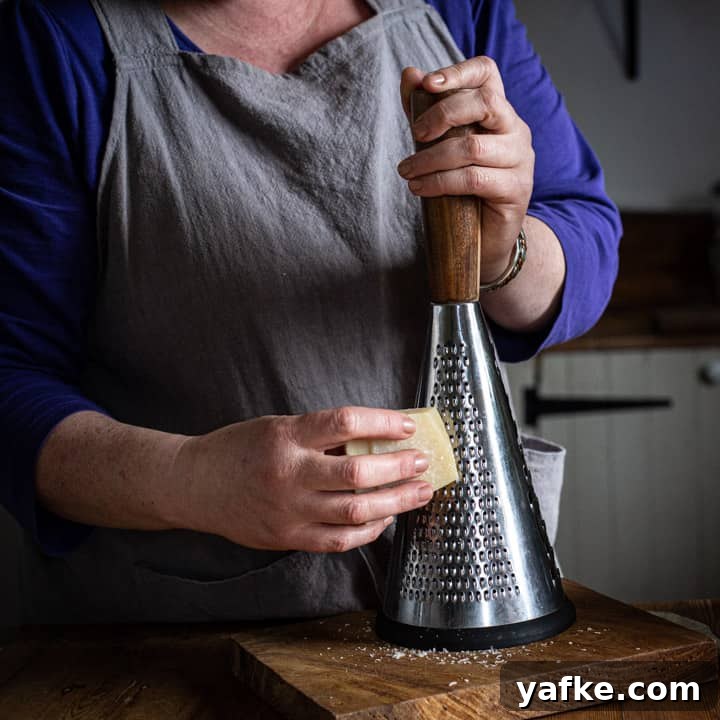 Wild Garlic Pesto Recipe for Spring 8 woman in grey grating a block of parmesan cheese onto a wooden board