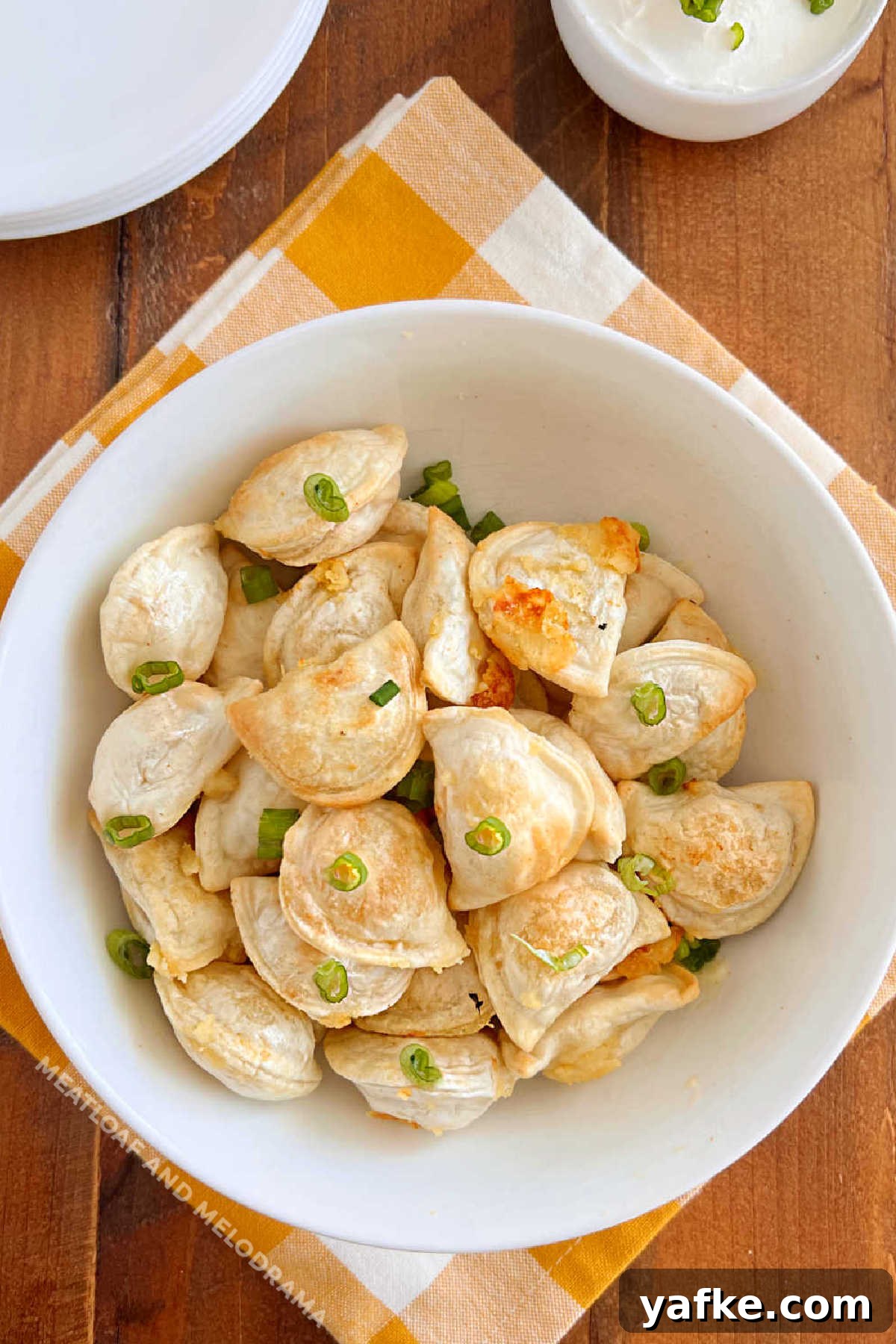 Crispy Air Fryer Pierogies in 15 Minutes 2 air fryer pierogies with onions in a white bowl on the table