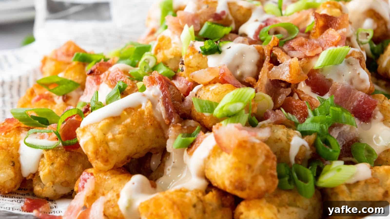 21 Fall Snacks I Tried: 9 Keepers 10 Loaded Tater Tots close-up topped with crumbled bacon, drizzled with ranch dressing, and garnished with sliced green onions on a white plate.