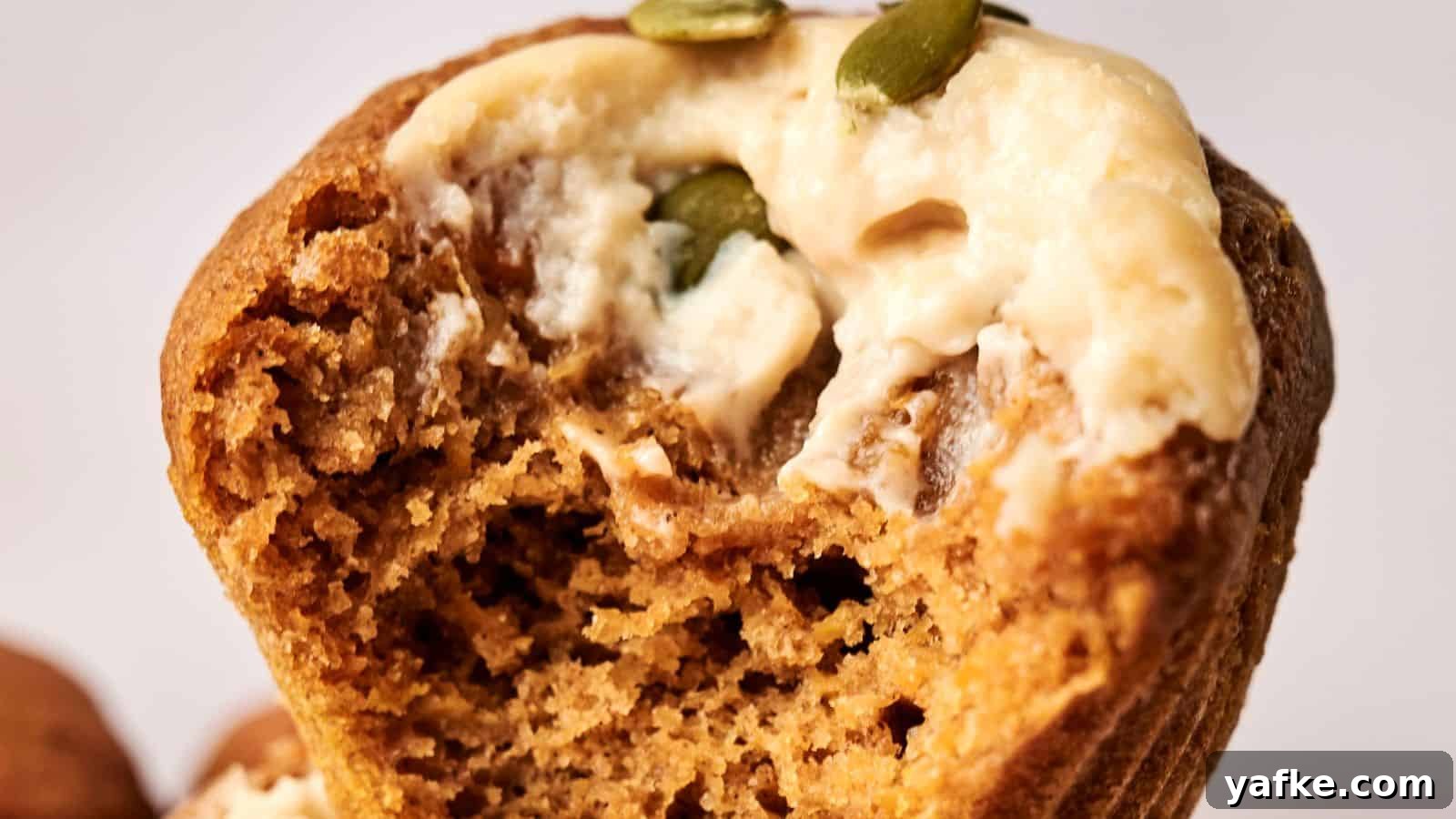 21 Fall Snacks I Tried: 9 Keepers 11 Close-up of a muffin with a bite taken out, topped with cream and pumpkin seeds.