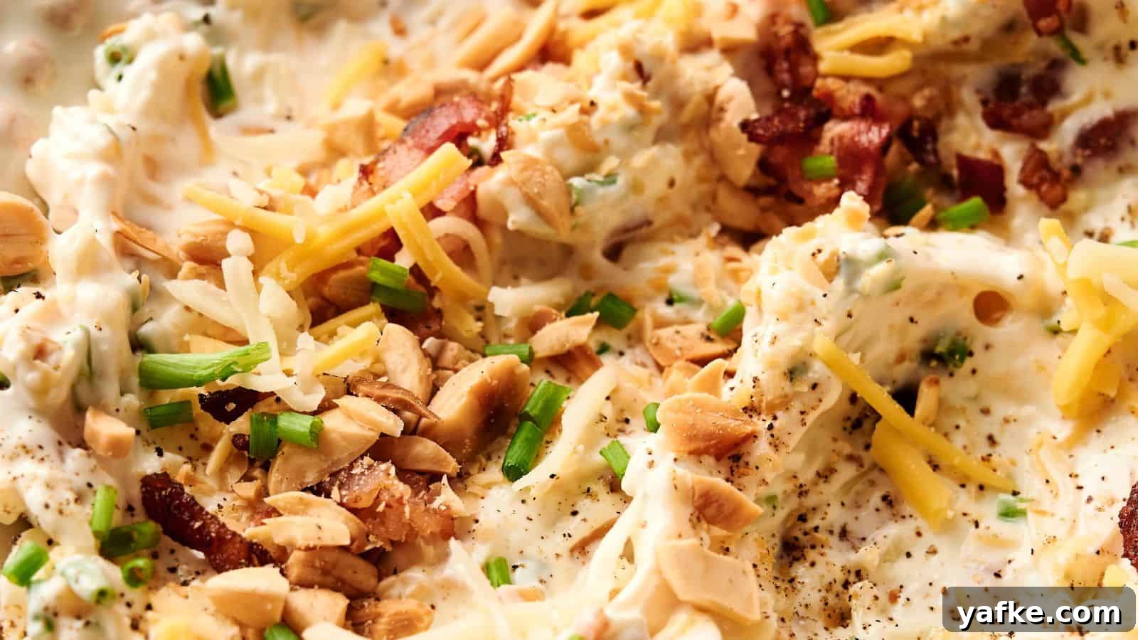 21 Fall Snacks I Tried: 9 Keepers 5 Close-up of a creamy dish topped with shredded cheese, chopped nuts, bacon bits, and sliced green onions.